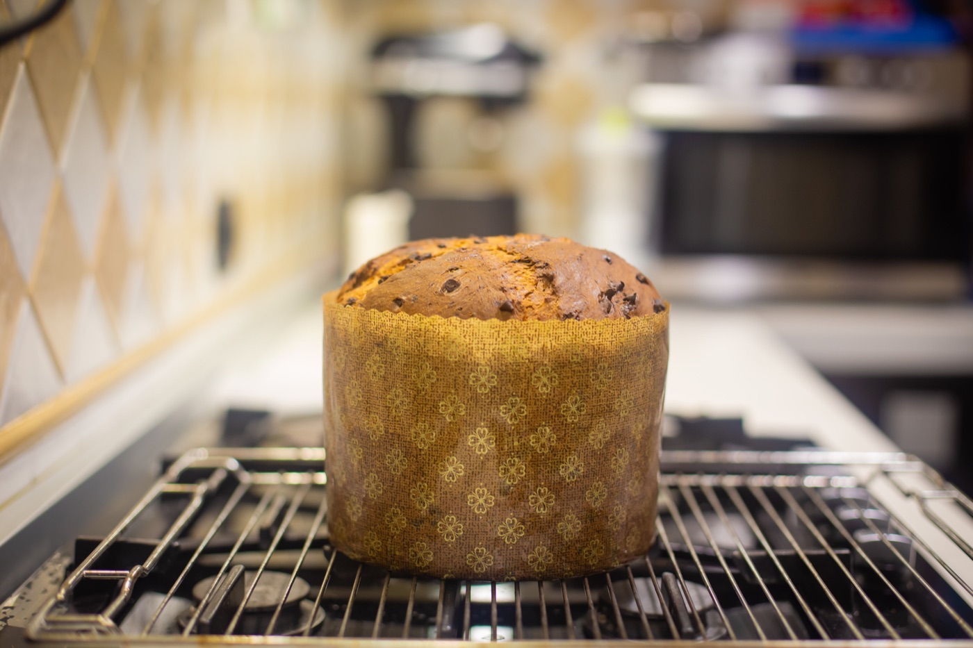 Panettone dalla cupola dorata appena sfornato, appoggiato su una griglia